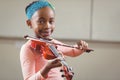 Smiling pupil playing violin in a classroom