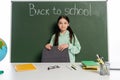 Smiling pupil standing near books on Royalty Free Stock Photo