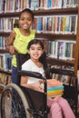 Smiling pupil in wheelchair holding books in the library