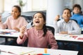 Smiling pupils taking off disposable medical face mask at classroom