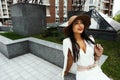 Smiling raven haired indian lady posing in backyard of high-rise building