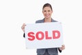 Smiling real estate agent presenting sold sign