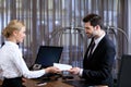 smiling receptionist giving envelope to businessman