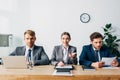 Recruiters with papers and laptop looking at camera at table