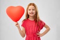 Smiling red haired girl with heart shaped balloon Royalty Free Stock Photo