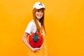 Smiling red-haired girl with a red handbag in the shape of an apple on a yellow background