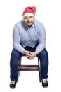 A smiling red-haired man in a Santa Claus hat is sitting on a unthinking chair. New Year and Christmas celebration. Isolated on a Royalty Free Stock Photo