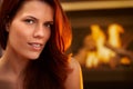 Smiling redhead beauty in front of fireplace Royalty Free Stock Photo