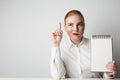 Smiling Redhead business woman posing in shirt holding empty notepad over white background. Royalty Free Stock Photo