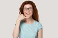 Smiling redhead girl in glasses show call phone gesture Royalty Free Stock Photo