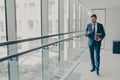 Smiling redhead man office worker in suit using cellphone while standing in modern office Royalty Free Stock Photo