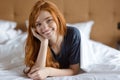 Smiling redhead woman lying in the bed