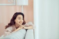 Smiling relaxed attractive woman wearing glasses sitting on a sofa looking back over her shoulder Royalty Free Stock Photo
