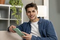 Smiling relaxed male using digital tablet at a modern apartment. Handsome carefree young man working with touchpad Royalty Free Stock Photo