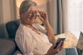 Smiling relaxed senior attractive woman with earphones sitting on sofa with laptop using mobile phone Royalty Free Stock Photo