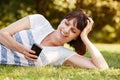 Smiling relaxed woman lying in grass with smart phone Royalty Free Stock Photo