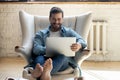 Smiling relaxed young man sit on armchair using laptop laughing Royalty Free Stock Photo