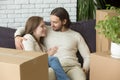 Smiling renters hugging on couch in new home with boxes