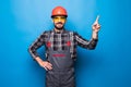 Smiling bearded repairman in overalls pointing on blue background Royalty Free Stock Photo