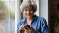 Smiling retired hispanic woman enjoy playing game in phone application Royalty Free Stock Photo
