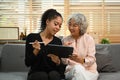 Smiling retried woman and her granddaughter surfing internet on digital tablet together on couch. Retirement, technology Royalty Free Stock Photo