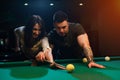 Smiling romantic couple playing snooker in club