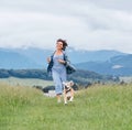 Smiling running beagle dog portrait with tongue out and happy owner female jogging by the mounting meadow grass path. Walking in Royalty Free Stock Photo