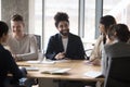 Smiling Indian businessman talking to clients at formal meeting