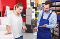 Smiling salesman offering door lock to young female in store Royalty Free Stock Photo