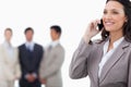 Smiling saleswoman on her mobile phone with team behind her Royalty Free Stock Photo