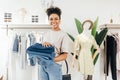 Smiling saleswoman standing in a small local store with a pile of jeans and looking away