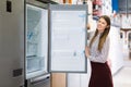 Smiling saleswoman suggesting refrigerator in store