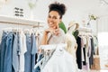 Smiling saleswoman working in boutique holding a bunch of hangers with clothes