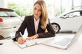 Smiling saleswoman writing on a clipboard