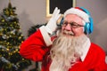 Santa claus listening to music on headphones at home Royalty Free Stock Photo
