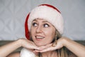 Smiling Santa girl wearing red hat is laying her chin on both hands looking up side. Portrait of beautiful young Royalty Free Stock Photo