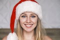 Smiling Santa girl wearing red hat looking at camera. Portrait of beautiful young blue-eyed blonde woman in Santa& x27;s Royalty Free Stock Photo