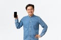 Smiling satisfied asian male freelancer, entrepreneur with own small business showing smartphone screen pleased. Guy