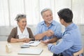 Smiling satisfied senior couple making sale purchase deal concluding contract hand get house key from real estate agent,happy Royalty Free Stock Photo