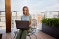 Smiling satisfied woman working on laptop at home balcony