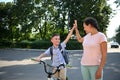 Smiling school boy giving high five to his African American mother. Child coming back to school. Kids on bicycle Royalty Free Stock Photo