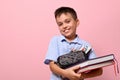 Smiling school boy posing over pink background with books and pencil case full of stationery. Back to school. Concepts with facial Royalty Free Stock Photo