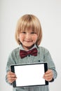 Smiling School boy in shirt with red bow tie, holding tablet computer in white background