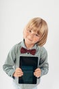 Smiling School boy in shirt with red bow tie, holding tablet computer in white background