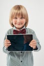 Smiling School boy in shirt with red bow tie, holding tablet computer in white background Royalty Free Stock Photo