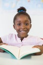 Smiling school girl reading book in classroom Royalty Free Stock Photo