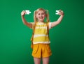 Smiling school girl showing puzzle pieces on green background Royalty Free Stock Photo