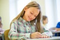 Smiling school girl writing test in classroom Royalty Free Stock Photo