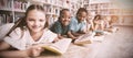 Smiling school kids lying on floor reading book in library Royalty Free Stock Photo