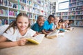 Smiling school kids lying on floor reading book in library Royalty Free Stock Photo